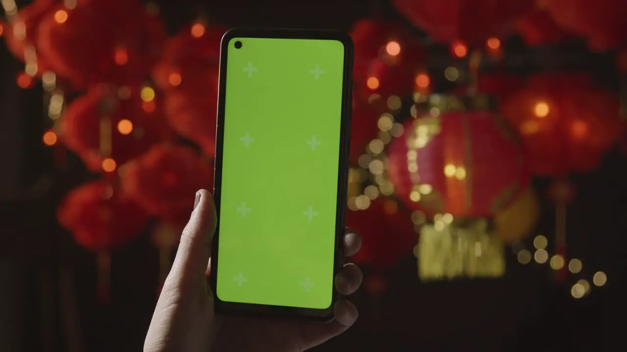 Hand Holding Green Screen Mobile Phone With Chinese Lanterns Hung In Background 4