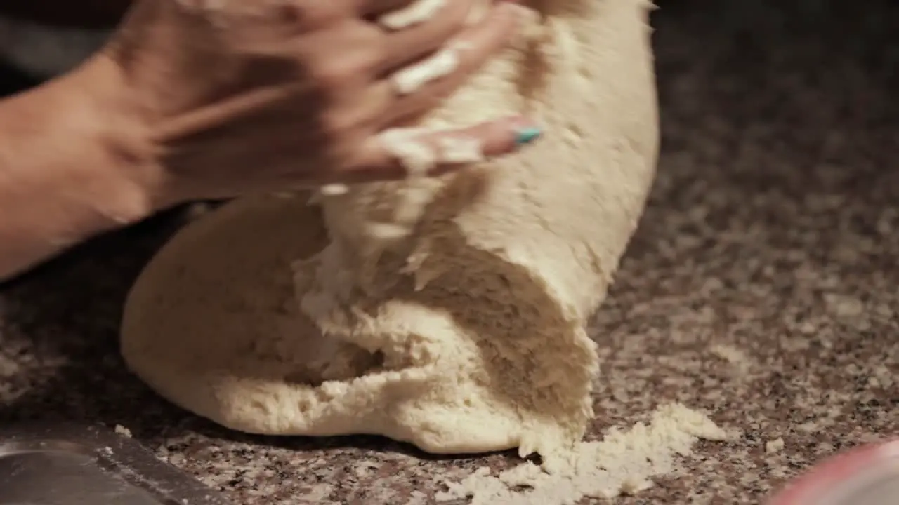 woman kneading dough with her own hands in a marble countertop