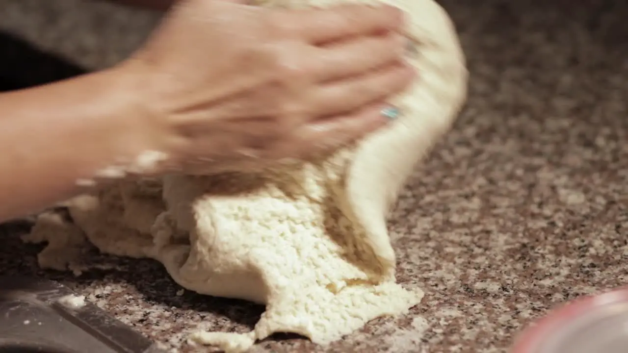 woman kneading dough with her own hands in a marble countertop in slow motion