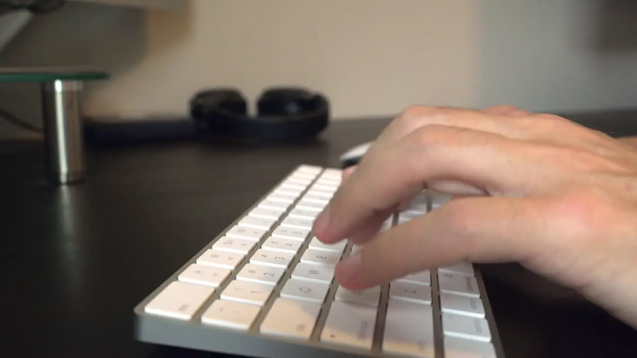 Close up slider shot of man typing on white keyboard and moving mouse