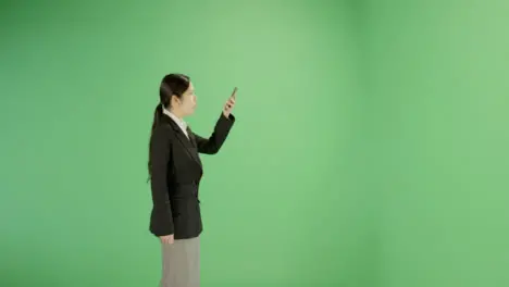 Businesswoman looking for phone signal on green screen