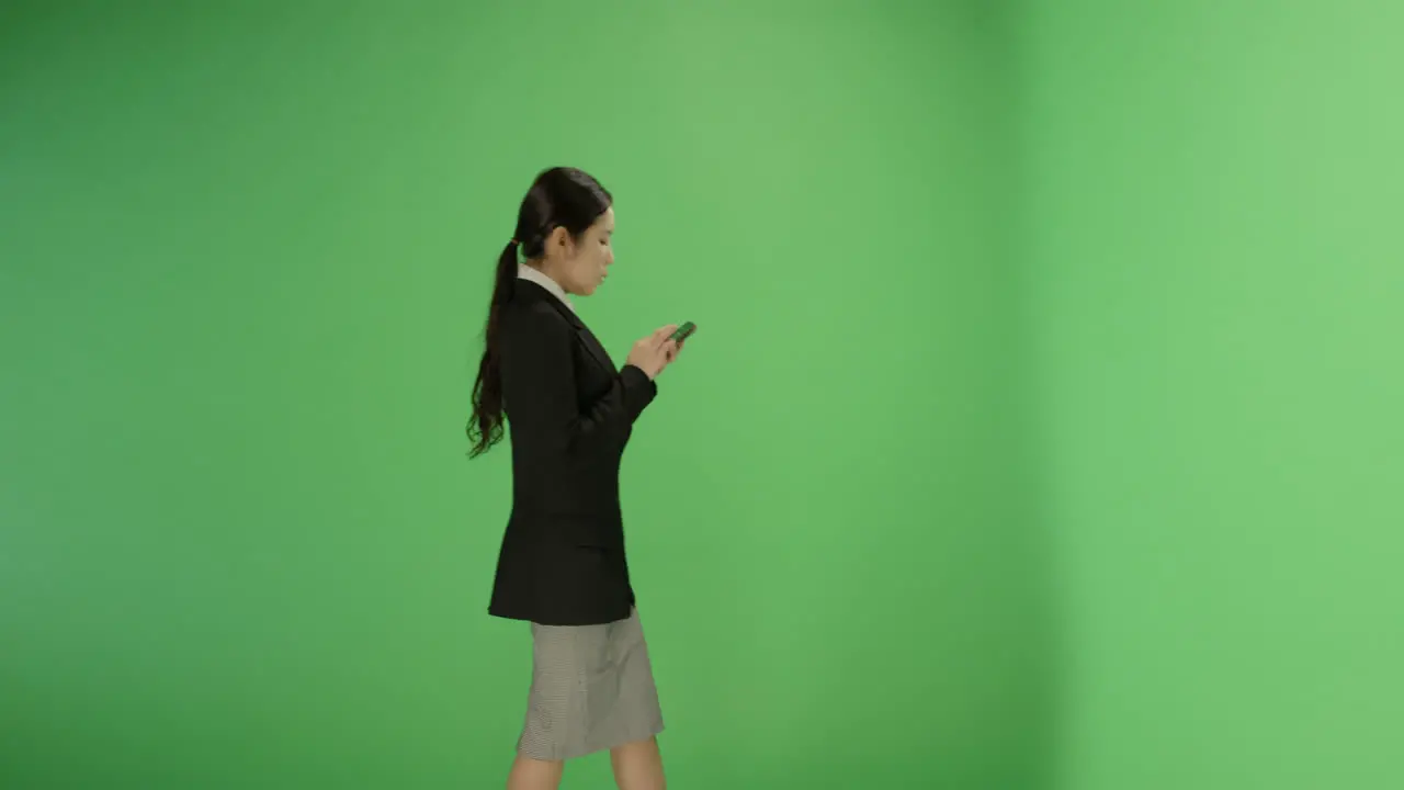 Businesswoman texting while walking on green screen