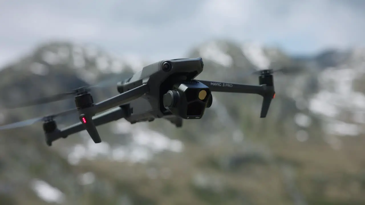 DJI Mavic 3 Pro Hovering In Air With Bokeh Background Of Snow Capped Mountains In Switzerland