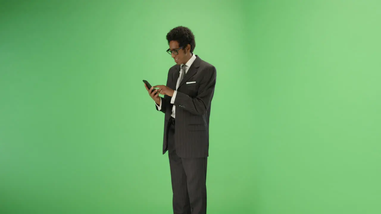 Smiling man sending message on phone with green screen