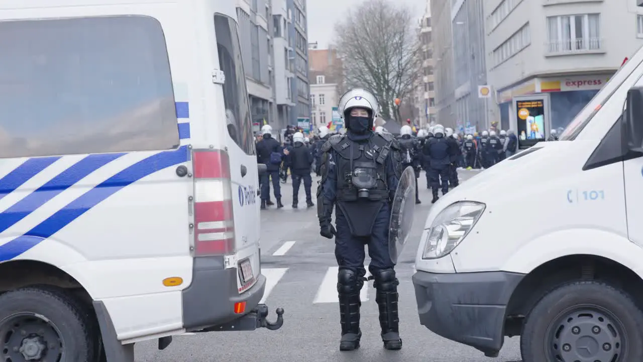 Female Police Officer Standing Between Two Vans During Protest In Brussels Belgium