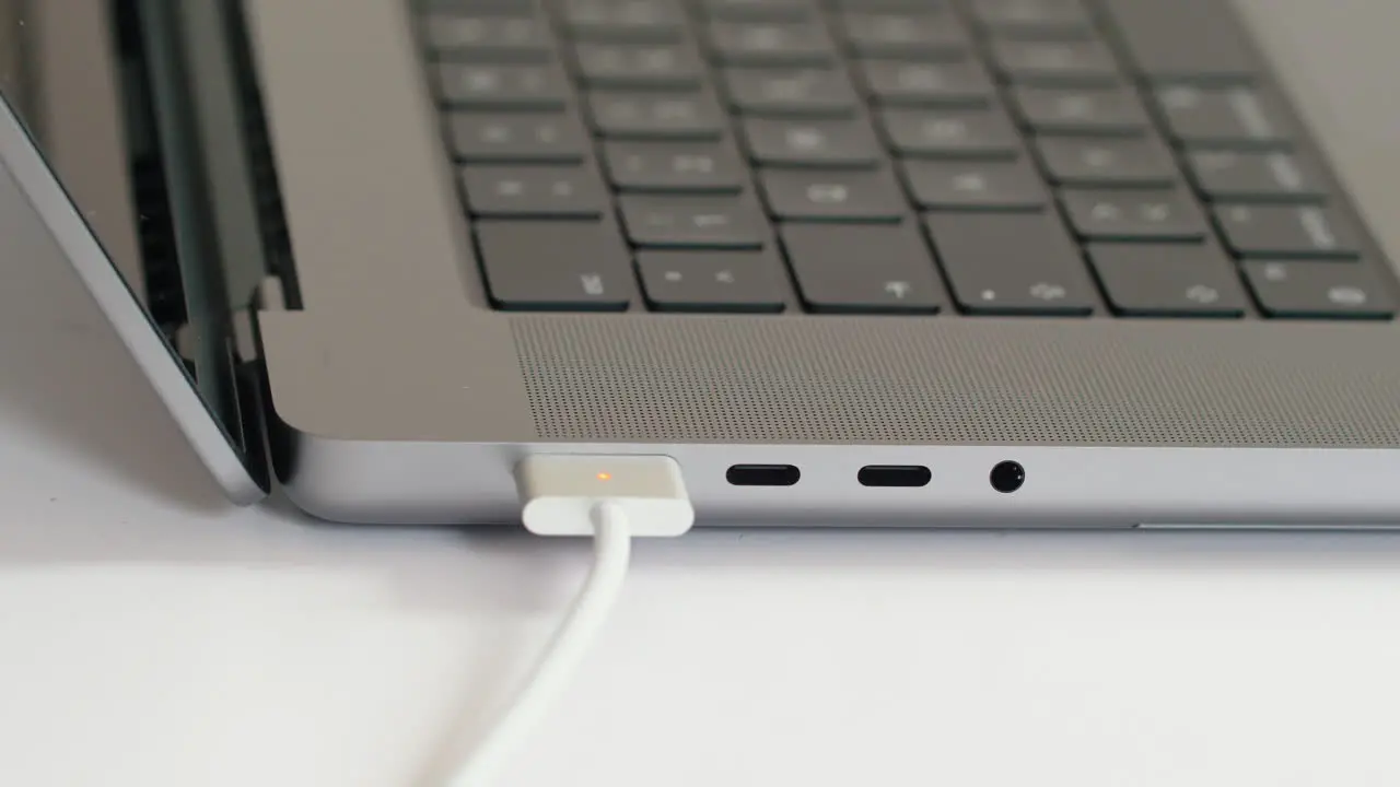 Close up person plugging in magsafe charger to new M1 MacBook Pro