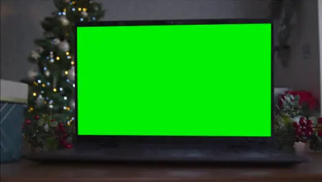 Close Up Shot of a Laptop Green Screen On Table In Front of Christmas Themed Background