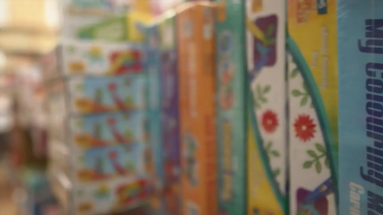 A dolly shot tracking backwards across a store shelf packed with different board games and puzzles in a toy shop