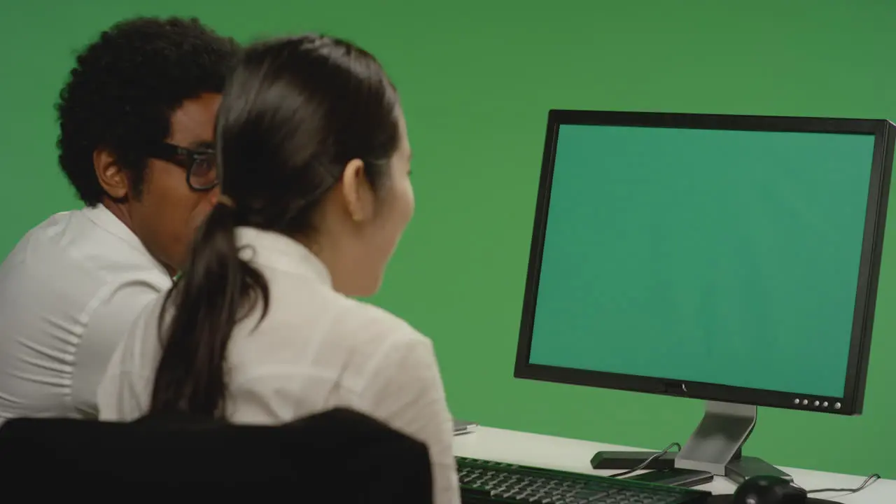 Colleagues look at computer and smile on green screen