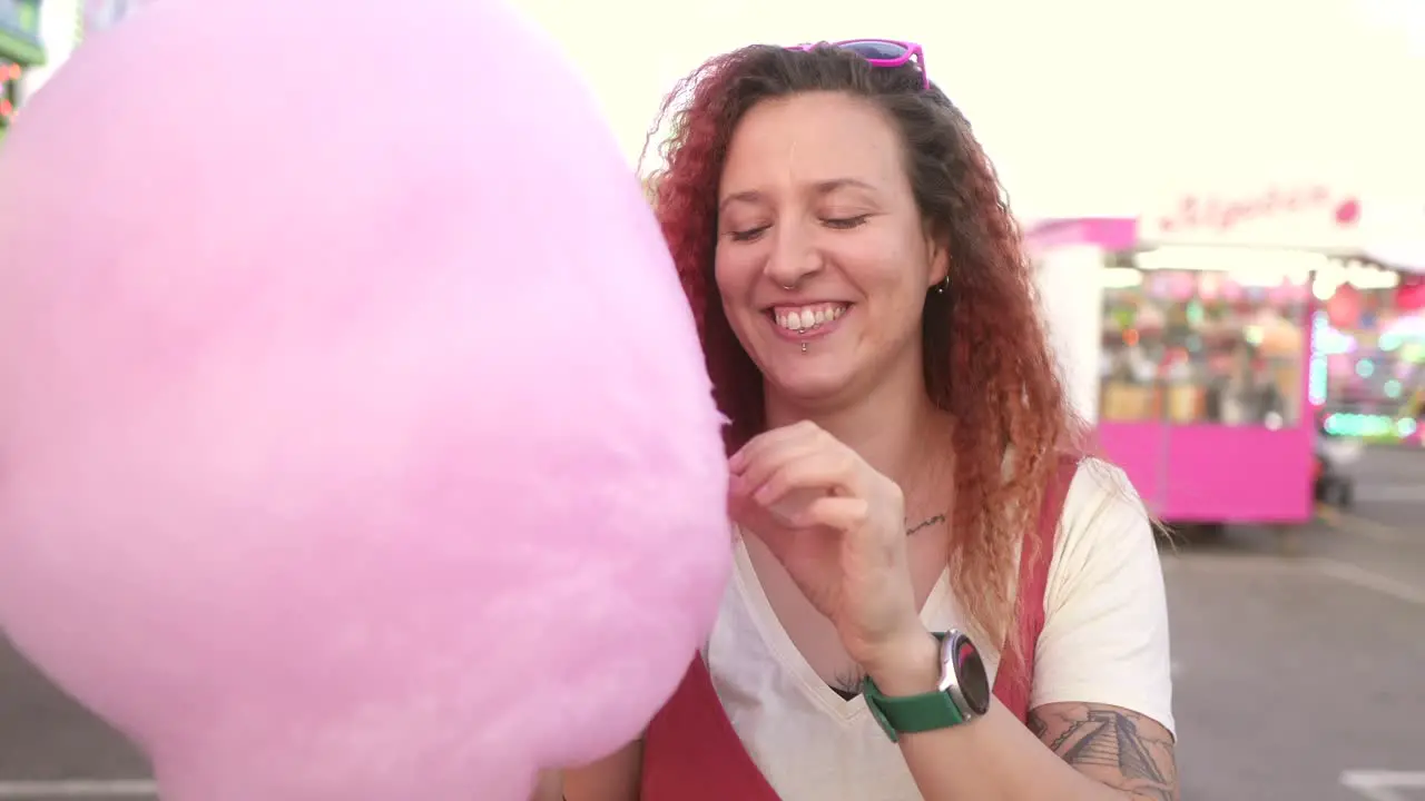 happy woman eating cotton candy at the fair