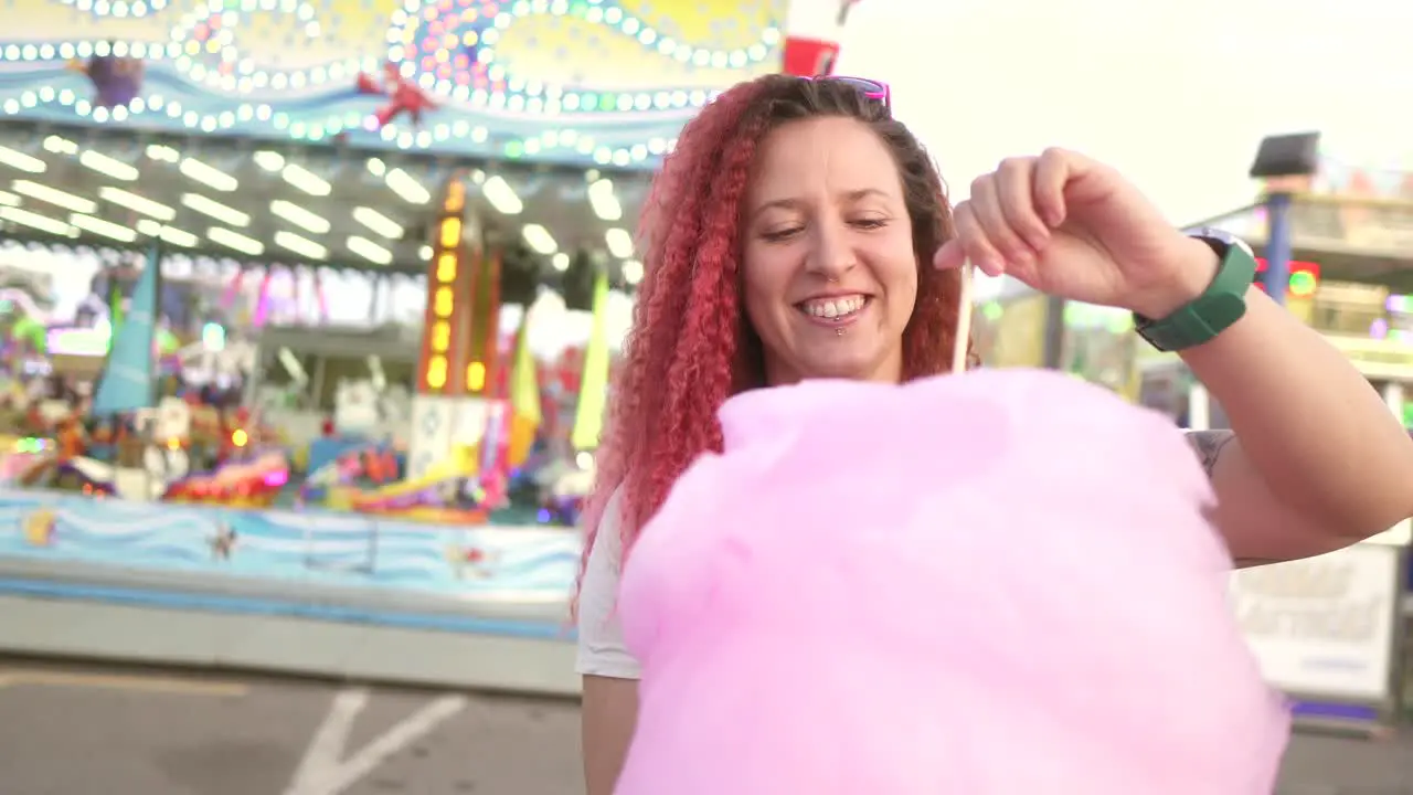 happy woman plays with cotton candy at the fair