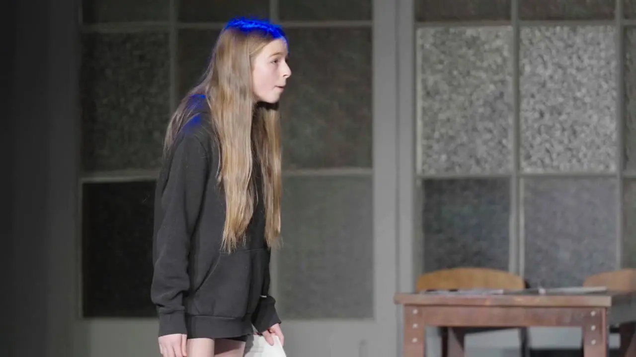 Young teenage actress performing on stage under theatre lights