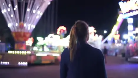 Back view of young attractive girl with ponytail walking forward then turning around smiling and looking at camera hanging out