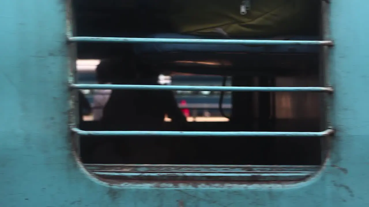 Moving departing train with passengers looking at camera out of window India