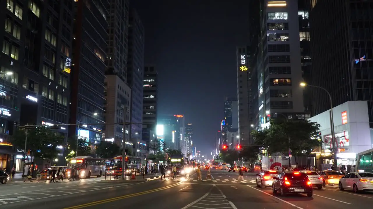 Buses And Cars Stopped As The Pedestrians Cross The Road At Gangnam District In Seoul At Night wide shot