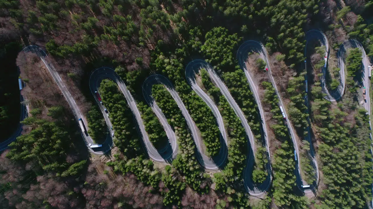 Slow aerial rise above traffic on winding road of Bratocea Pass Romania