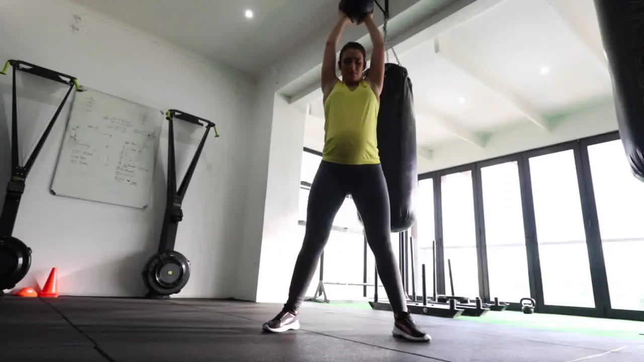 Pregnant female fitness model doing body weight exercise in a gym to keep fit during her third trimester of pregnancy-1