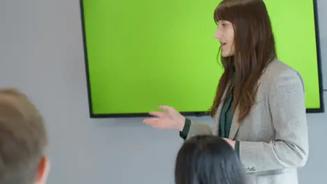 Businesswoman Presenting To Colleagues Using Green Screen Tv