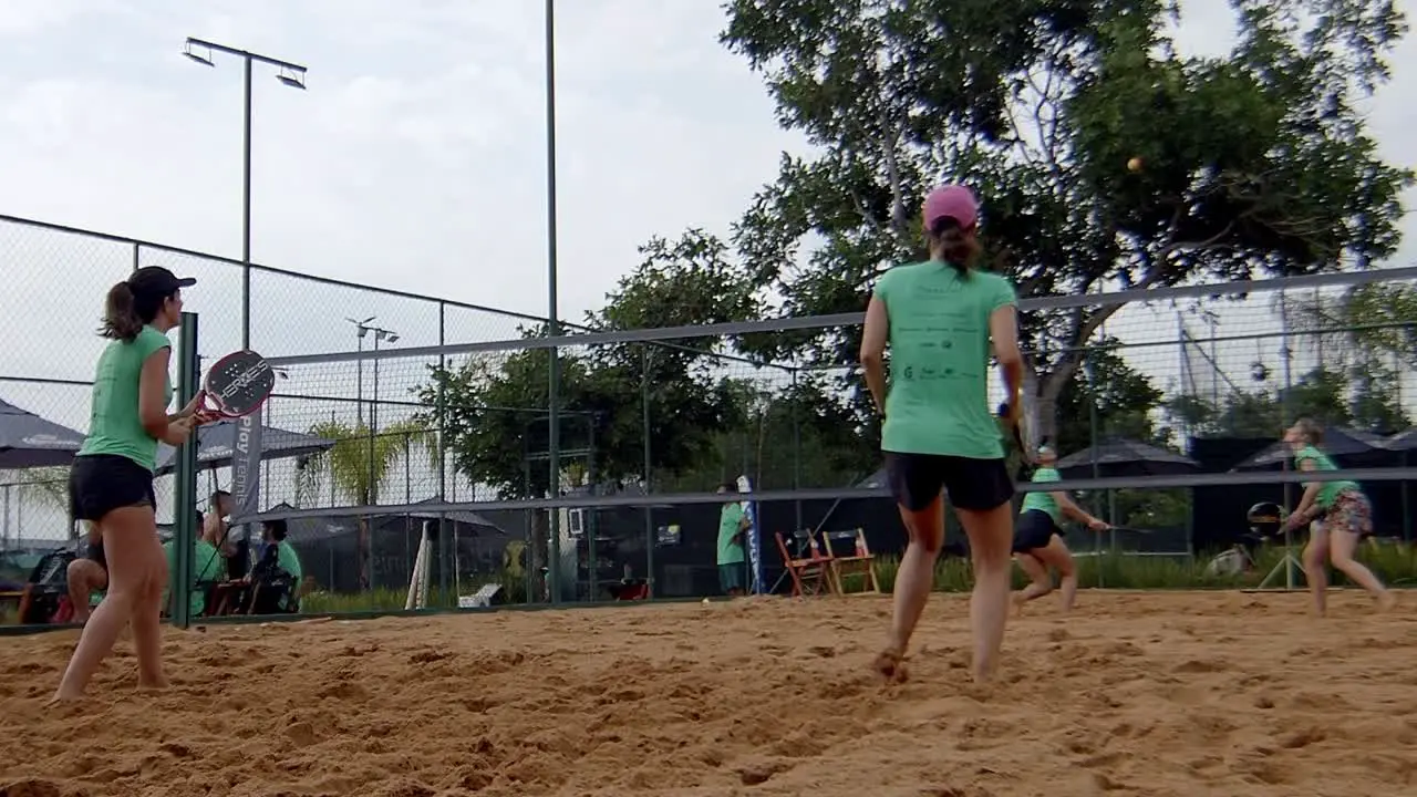 padel contest female friends playing ball in padel match smashing and jumping on sunny beach padel sandcourt