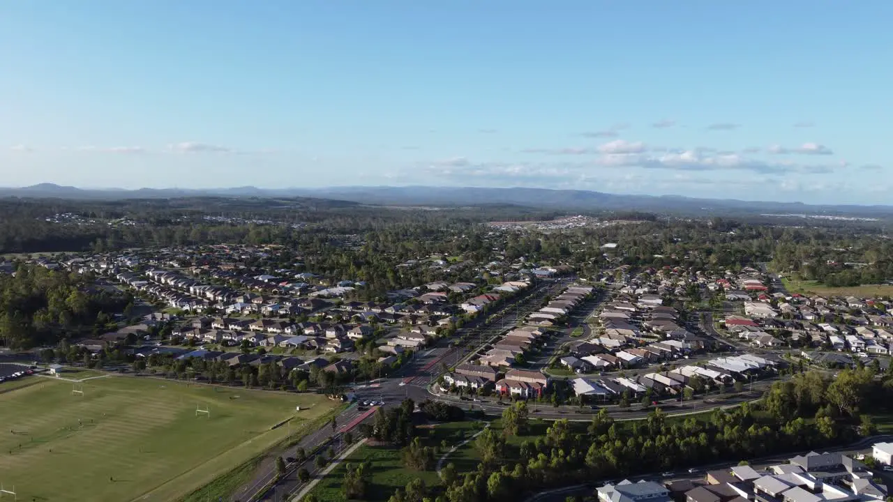 Aerial footage of football field and an intersection with small town and mountains in the background