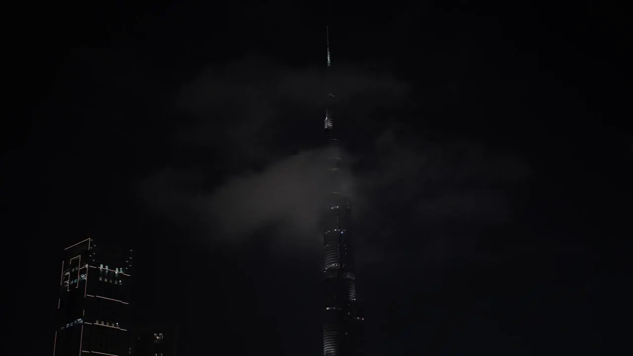 Clouds pass by the top of the Burj Khalifa in downtown Dubai at night time