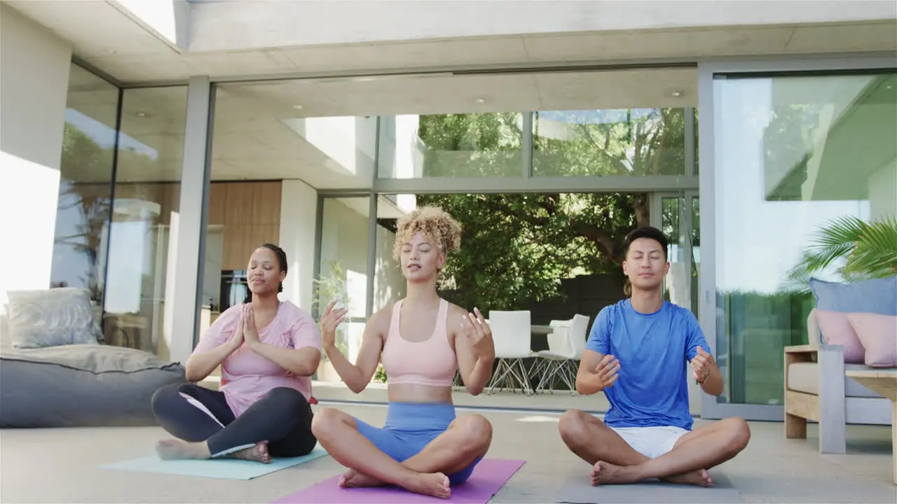 Young biracial women and Asian man meditate at home