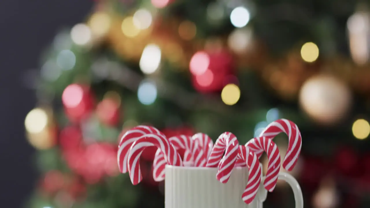 Video of white mug with christmas cnady canes and christmas tree lights with copy space