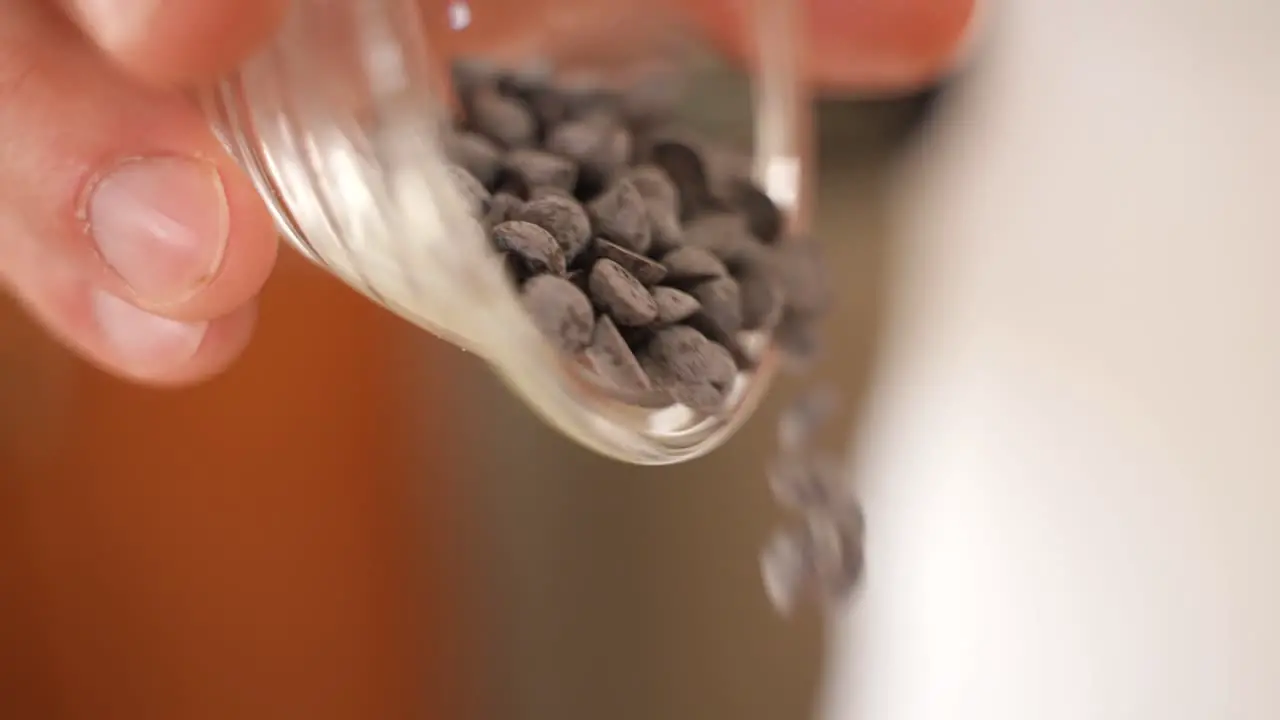 Pouring Chocolate Chips from Plastic Cup Close Up in Slow Motion with Copy Space