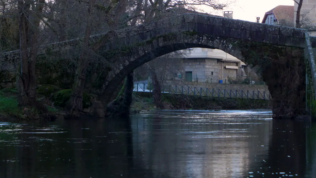 Static view of curved arch on triangular roman bridge crossing Molgas River