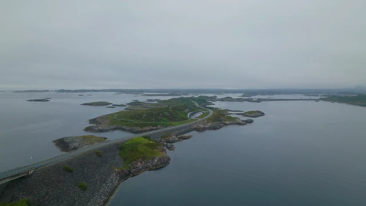 Drone trucking pan rises above scenic Atlantic Ocean road at a misty grey dusk