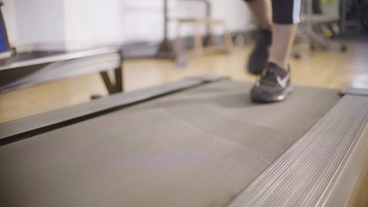 Asian girl comes and steps on treadmill with sports shoes on at gym