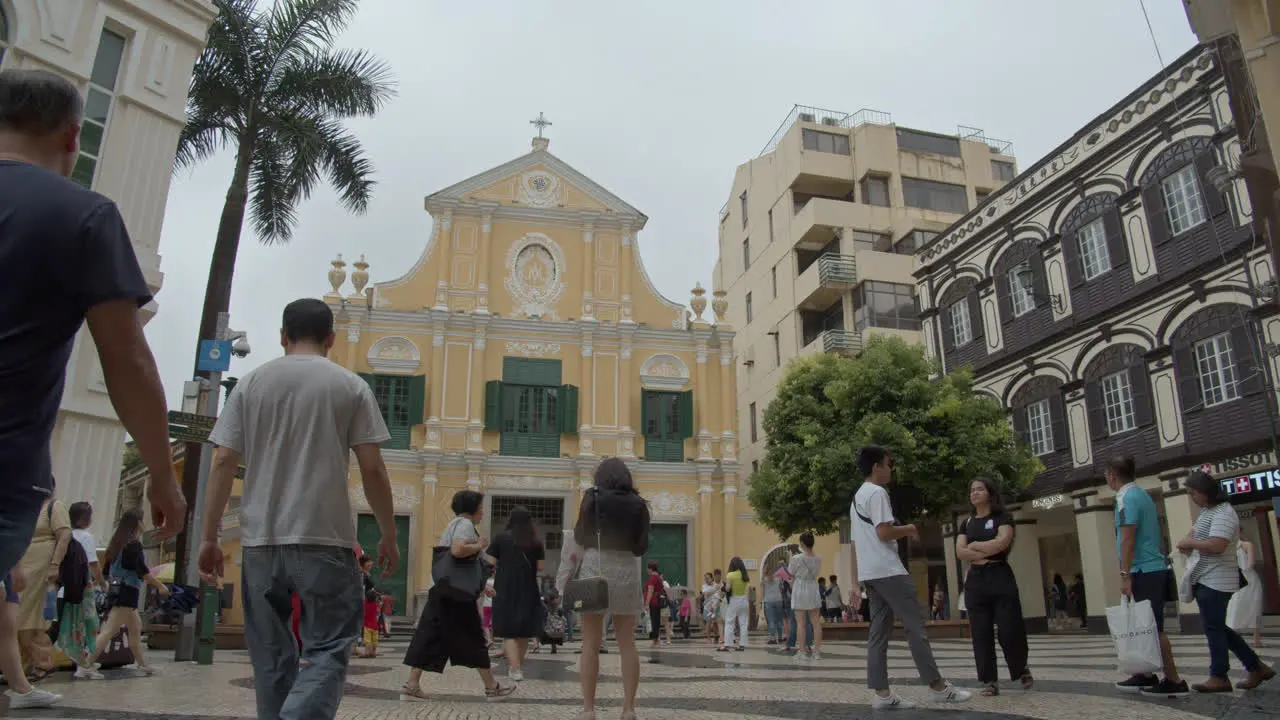 Tourists walking at the small square near yellow colored Baroque-style St