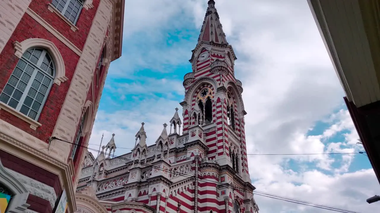 A beautiful Cathedral with red and white stripes and a clock on the dome on the old town of Bogotá Colombia