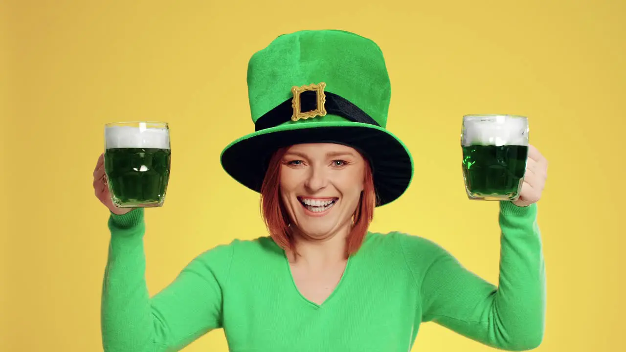 Smiling woman with leprechaun's hat holding full a beer glass