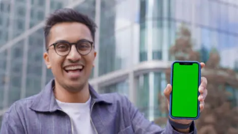 Low Angle Shot of Young Man Holding Green Screen Smartphone