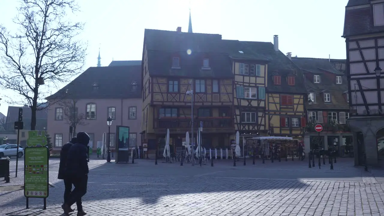 People walking on pedestrian cobblestone square with traditional half-timbered medieval and early Renaissance buildings