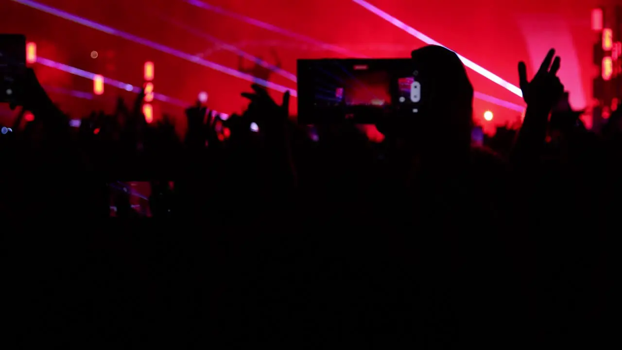 Silhouetted Fans at Nighttime Music Concerts Recording Videos Holding Smartphones and Dancing with Lights