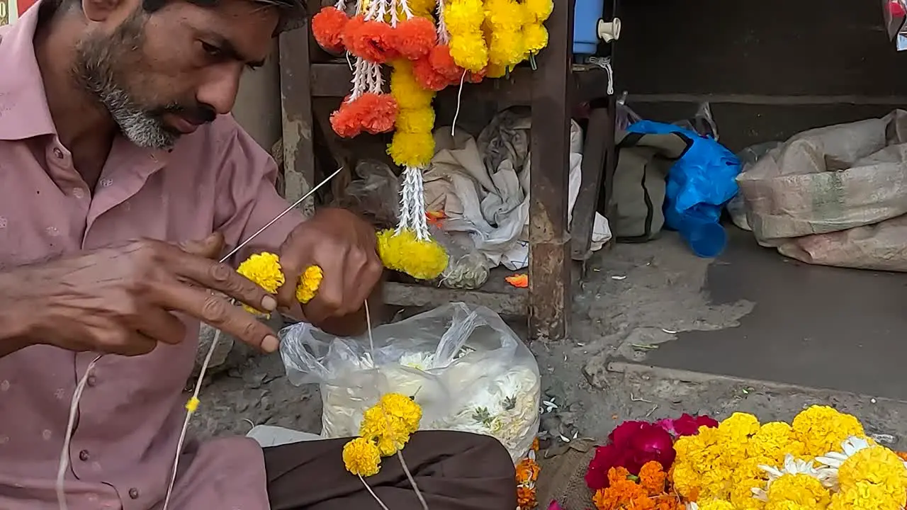 Close up view a shopkeeper is making fresh flower garlands on the street road