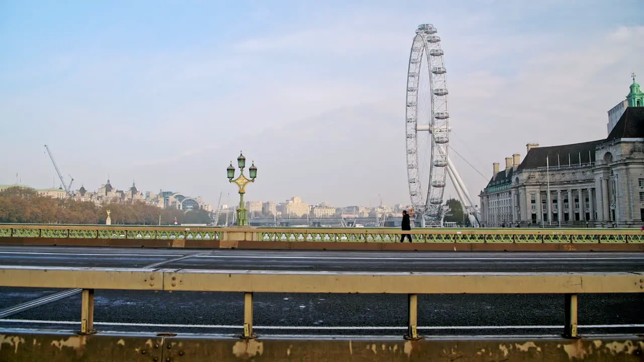 Quiet and empty roads at rush hour in London in Coronavirus Covid-19 lockdown with deserted streets at Westminster Bridge and London Eye no traffic and one person walking for rush hour commute