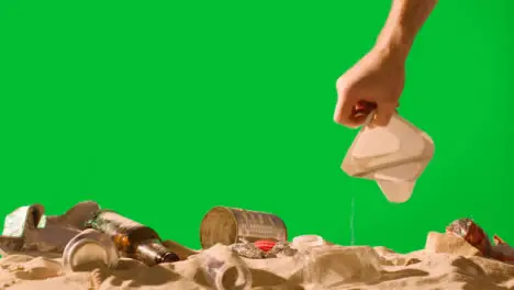 Pollution Concept With Hand Picking Up Bottles And Rubbish On Beach Against Green Screen