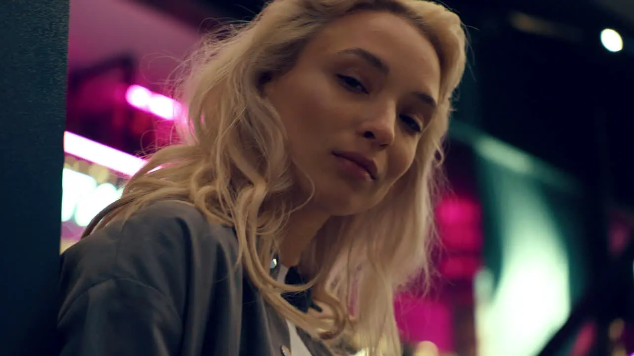 Blonde model face looking camera in neon lights in night city