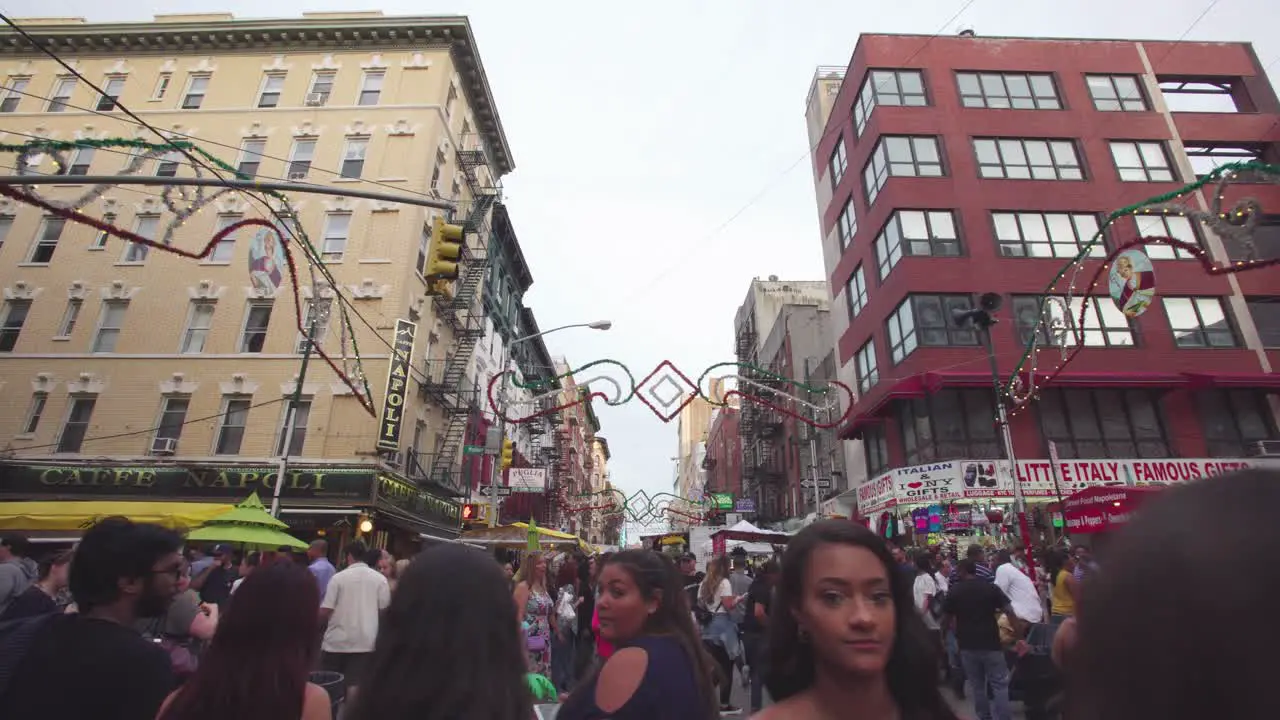 NYC Little Italy street market at an intersection in the middle of a crowd surrounded by food stalls and games Gimbal push forwards New York City USA