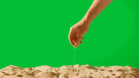 Summer Holiday Concept With Hand Picking Up Shells Starfish On Sandy Beach Against Green Screen