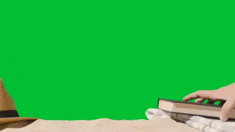 Summer Holiday Concept Of Book Sun Hat Beach Towel On Sand Against Green Screen 1