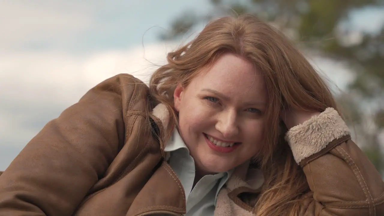 Portrait Of A Sexy Red Haired Woman Lying Outdoors Looking Directly At The Camera