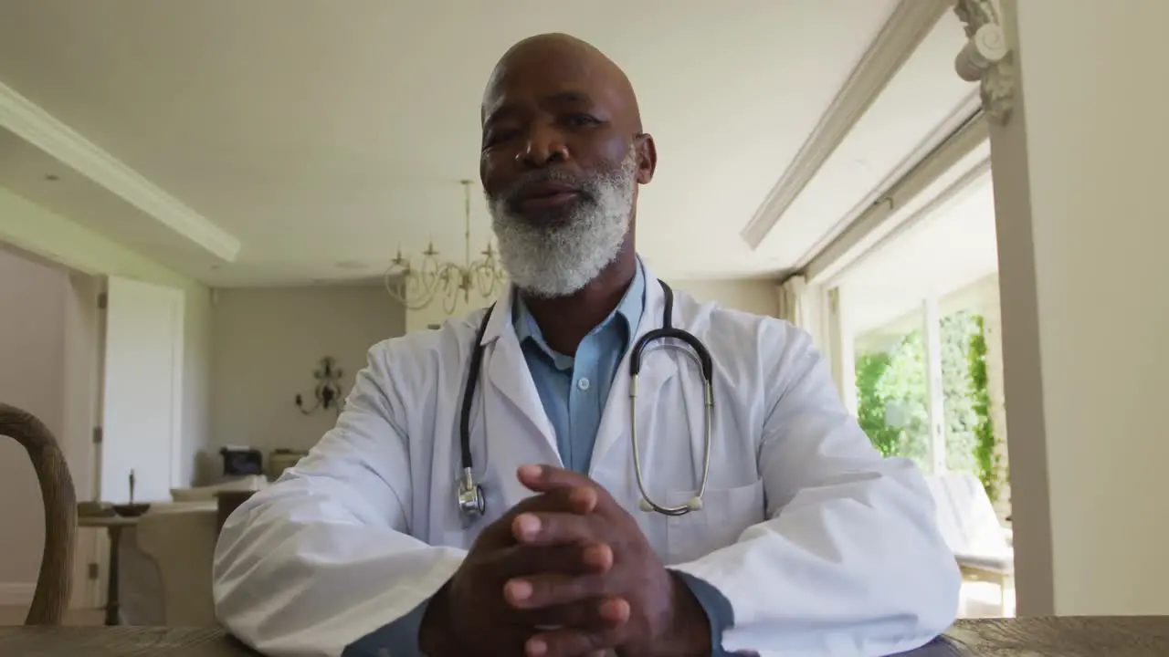 Portrait of african american senior male doctor talking looking at the camera at home