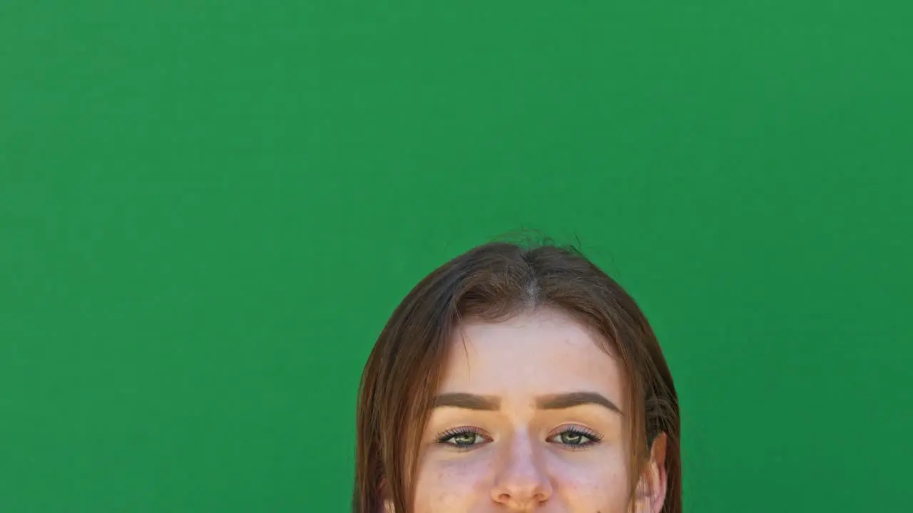 Close-up of a young brunette woman which is standing in front of a green screen