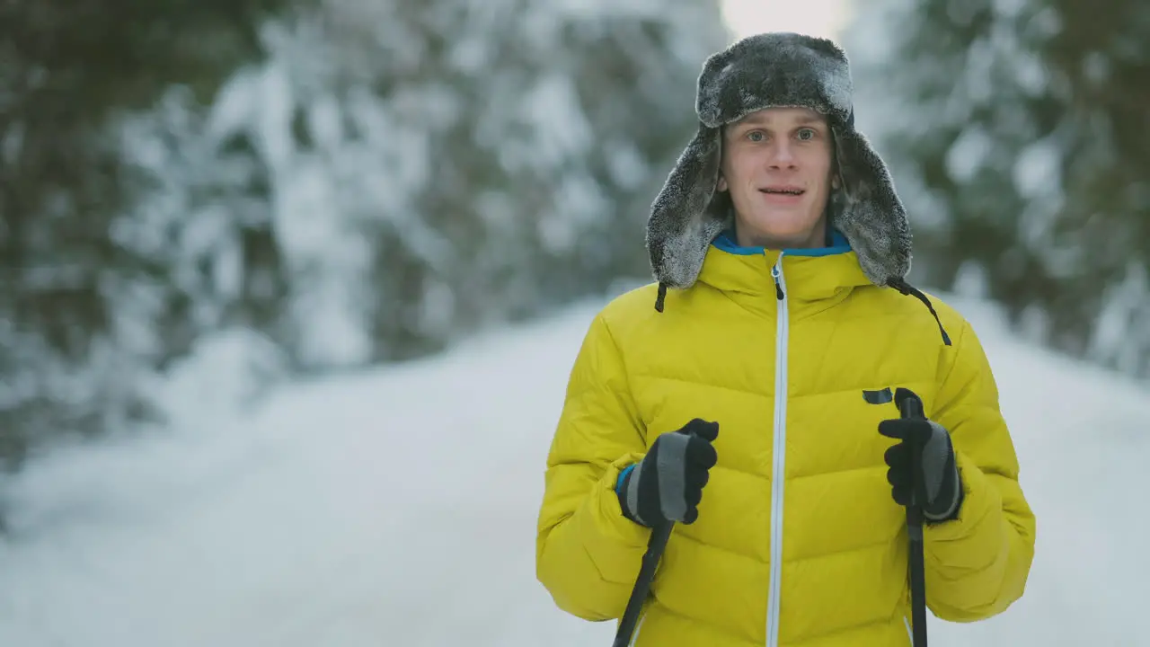 Smiling man with skis and his wife looking at something curious during trip in winter forest