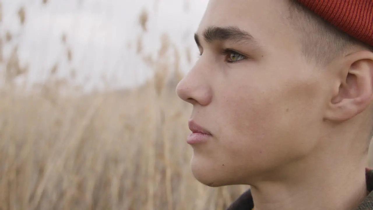 Close Up View Of A Teenage Boy With Orange Beanie And Plaid Coat Looking At Side In A Wheat Field