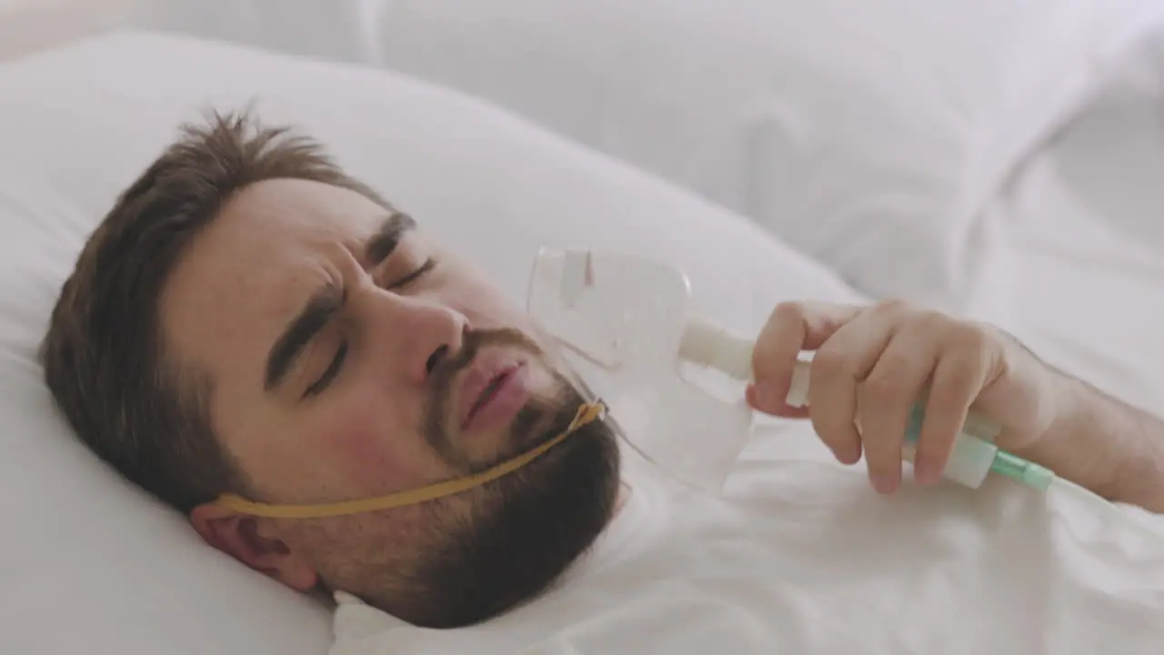 Sick Man Lying On Bed Taking His Oxygen Mask Off And Coughing 2